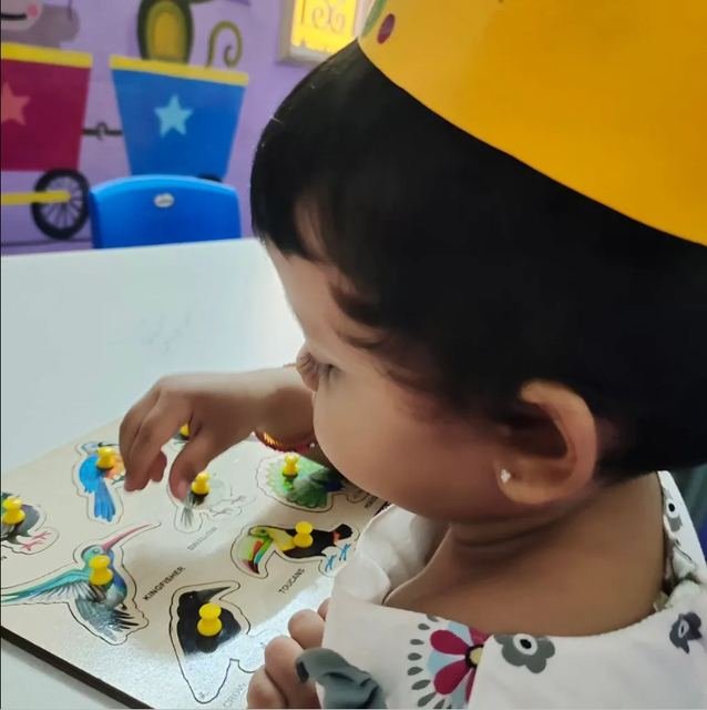 Child engaged in a bird puzzle learning activity at Kids Kingdom Playschool